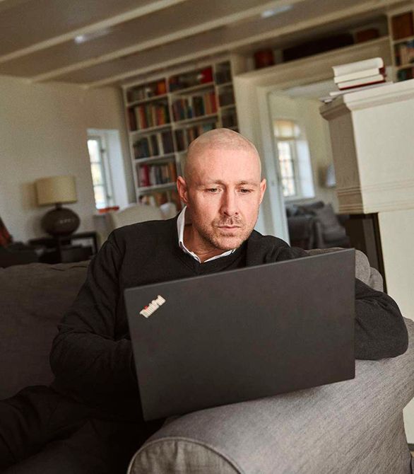 En mand sidder i en sofa og læser på sin computer
