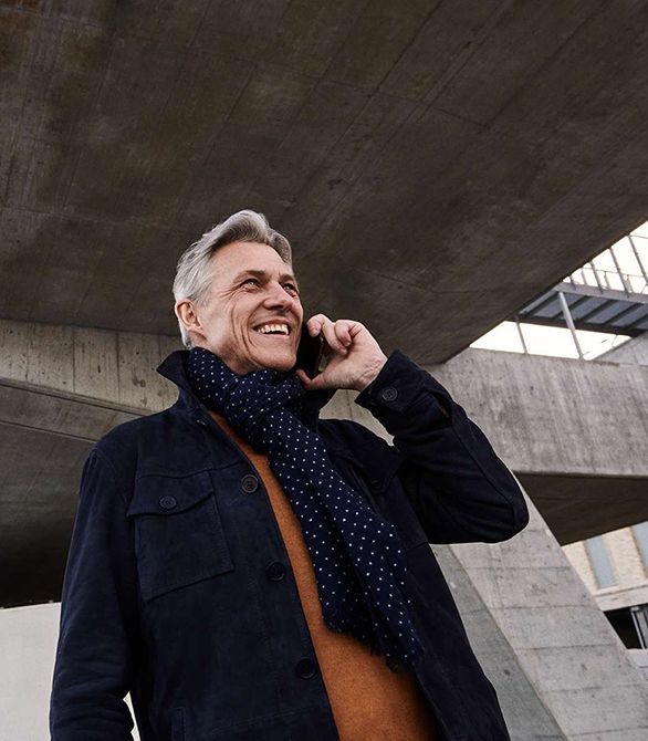 Smilende mand med halstørklæde taler i telefon udenfor