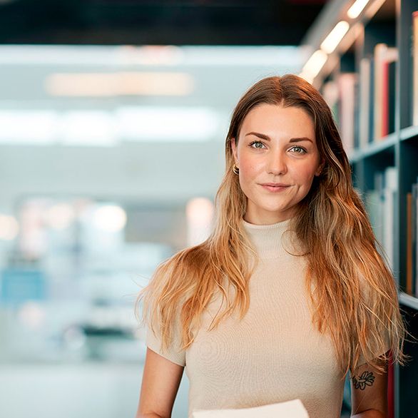 En ung kvinde står på et bibliotek