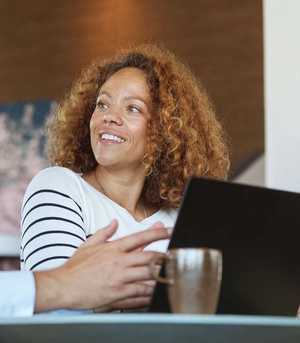 Kvinde sidder med sin bærebare computer og smiler til sin sidemand